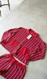 Short de punto a rayas verticales rojas, blancas y negras, con cintura elástica y cordón ajustable.