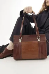 Cartera tipo shopper de cuero genuino marrón con panel central de textura símil cocodrilo y herrajes metálicos plateados.