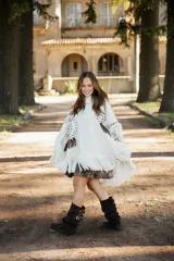 Poncho de lana merino color crudo con cuello alto, diseño amplio y flecos en el ruedo. Presenta bordados decorativos en tono chocolate y detalles de flecos en los hombros.