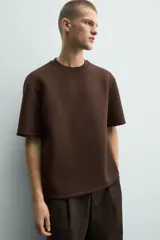 Sudadera de manga corta con corte relajado, confeccionada en tejido técnico compacto de algodón con elasticidad. Presenta cuello redondo y detalle de tacha metálica en la espalda.