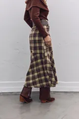 Falda midi de corte evasé con estampado de cuadros escoceses en tonos marrones y beige. Presenta un diseño asimétrico en el ruedo y cierre lateral.