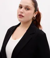 Blazer negro de corte slim alargado, confeccionado en punto roma con abotonado doble frontal, solapas de muesca y bolsillos de ojal en los laterales.