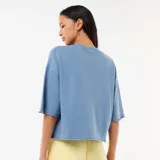 Camiseta de felpa color azul con mangas 3/4, cuello redondo y diseño holgado con terminaciones rústicas.