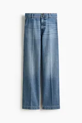 Pantalón de jean de tiro alto con corte wide leg, confeccionado en denim de algodón rígido. Presenta cierre frontal con doble botón, pasacintos y pliegues marcados en la parte delantera y trasera.