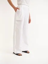 Pantalón blanco de lino con diseño de corte recto y amplio, bolsillos laterales superpuestos y cintura elástica.
