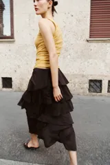 Falda midi de tiro medio con cintura elástica y diseño de múltiples volantes en capas. Presenta un bajo asimétrico y una caída fluida.