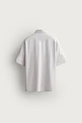 Camisa azul marino de corte regular fit confeccionada en tejido fluido de algodón y lino, con cuello solapa, manga corta, bolsillo aplicado en el pecho y cierre frontal con botones.