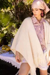 Ruana color crudo tejida a mano en mezcla de lana y seda, con flecos largos.
