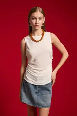 Musculosa blanca sin mangas de poliéster, con cuello bote y diseño ajustado al cuerpo.
