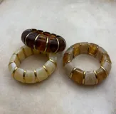 Pulsera elástica de diseño modular compuesta por piezas de resina con efecto marmolado y separadores metálicos dorados.
