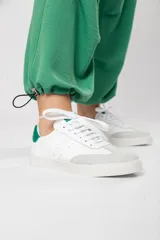 Zapatillas acordonadas de cuero color blanco con puntera de gamuza gris y detalles en verde.