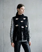 Chaleco tejido en lana merino, color negro, con cuello alto y diseño sin mangas. Presenta aplicaciones artesanales en relieve que simulan ovejas y un ruedo terminado con largos flecos.