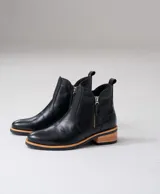 Botas cortas de cuero vacuno color marrón, con diseño de caña baja y cierre metálico en ambos laterales. Presentan un taco cuadrado de madera y suela de goma.