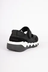 Zapatillas tipo guillerminas negras con recortes en símil cuero y tela, con velcro y pespuntes a tono.