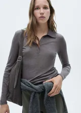 Polo de manga larga confeccionado en tejido de punto fino, con cuello clásico y cierre frontal de botones. Presenta un diseño entallado y acabado acanalado.