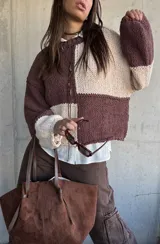 Sweater de punto con diseño de bloques de color en tonos chocolate y beige, de corte holgado y mangas largas con puños ajustados.