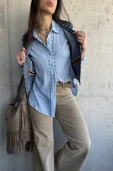 Camisa celeste de manga larga con bordados geométricos frontales a lo largo de la botonadura, cuello camisero clásico y cierre frontal de botones.