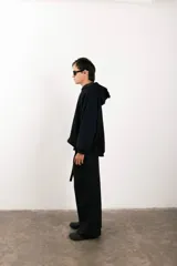 Buzo negro de corte amplio con capucha y detalle de parche circular en el pecho.