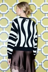 Sweater de punto con estampado de rayas onduladas en blanco y negro, cuello polo con botones y mangas largas.