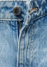 Jeans tiro medio color celeste, de diseño recto y largo, con bajo vuelto, trabillas, cierre de botón y cremallera, estilo cinco bolsillos y detalle de costuras verticales.