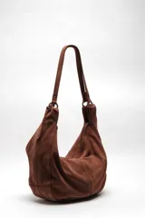 Bolso tote de ante suave, de cuerpo blando estilo hobo, con asa larga para el hombro y cierre superior con cremallera.