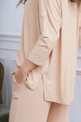 Remerón de tela acanalada color beige, con corte holgado, mangas tres cuartos y aberturas laterales en el ruedo.