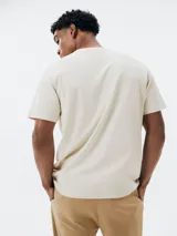 Camiseta beige de corte regular con bolsillo en el pecho y bordado de montañas.