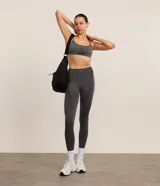 Legging deportiva de tiro alto confeccionada en tejido seamless color gris melange. Presenta un diseño ajustado con paneles texturizados en los laterales que ofrecen un efecto modelador y levanta pompis.