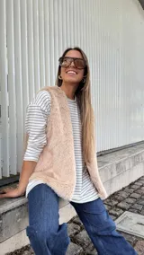 Chaleco de piel sintética en color beige, con diseño sin mangas, corte recto y silueta amplia. Cuenta con forro interior y bolsillos laterales.