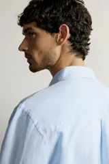 Camisa regular fit celeste confeccionada en mezcla de lino y algodón, con cuello abotonado, manga larga, bolsillo frontal en el pecho y cierre de botonadura.