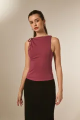 Top sin mangas de viscosa color negro, ajustado al cuerpo, con cuello redondo y frunces asimétricos en el hombro izquierdo.