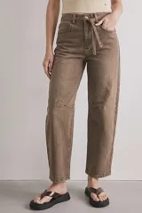 Jean barrel tiro alto en color marrón, confeccionado en denim con lavado artesanal. Presenta corte amplio en las piernas, bolsillos clásicos y un lazo fino desmontable en la cintura.