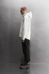 Cazadora deportiva de ajuste regular, confeccionada en tejido técnico de tres capas con membrana impermeable (resistencia al agua ≥15K) y costuras termoselladas. Presenta cuello subido con capucha ajustable, manga larga con puños ajustables con tira adherente, aberturas con cremallera termosellada en axilas para ventilación, bolsillos frontales con cremallera termofijada y bajo ajustable con elásticos laterales.