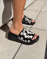 Zueco de mujer con plataforma negra y capellada tejida en patrón de damero blanco y negro con textura de pelo.