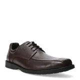 Zapato de vestir para hombre, color marrón oscuro, con cordones y suela plana de goma. Presenta costuras decorativas en la puntera y un pequeño logo metálico en el lateral.