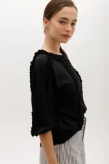 Blusa blanca de algodón suave, con mangas 3/4 y escote redondo con volados en el frente, mangas y escote.