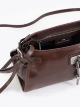 Bandolera de cuero vacuno color marrón con acabado brillante. Presenta un diseño estructurado con herraje metálico tipo candado y llave colgante en el frente, además de detalles de tiras laterales. Incluye correa de hombro y cierre superior.