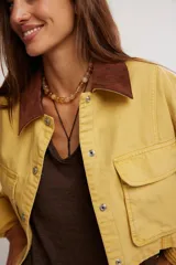 Campera corta de sarga de inspiración workwear, color amarillo con cuello en contraste marrón, bolsillos con solapa en el pecho y cierre frontal con botones.