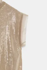 Top color tostado decorado con lentejuelas en el frente, cuello redondo y mangas sisa con detalles semitransparentes en cuello y sisas. Cuenta con cierre en la espalda con abertura y lazada.