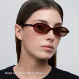 Lentes de sol con montura ovalada de color negro y cristales polarizados en tono marrón. Presentan un diseño estilizado y ligero con protección UV400.