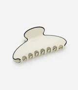 Pinza para el pelo de tamaño grande, fabricada en acetato color crema con un borde negro contrastante.