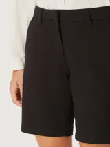 Bermuda negra de tiro medio confeccionada en sarga de algodón y elastano, con diseño tipo chino y corte casual.