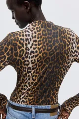 Top de punto con cuello alto y manga larga, con diseño de estampado de leopardo y terminaciones con remate sobrehilado en puños y bajo.