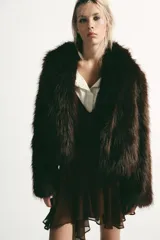 Abrigo corto de Zara confeccionado en pelo sintético de textura suave, color marrón oscuro. Presenta cuello solapa, manga larga y cierre frontal con ganchos metálicos ocultos.