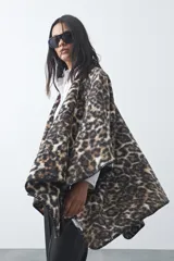 Poncho de silueta amplia con estampado animal print, bordes terminados con costura decorativa y diseño envolvente.