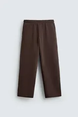Pantalón jogger de corte relajado y pernera ancha, confeccionado en tejido de algodón con interior perchado. Cuenta con cintura elástica ajustable mediante cordón interior, bolsillos laterales y un bolsillo trasero de plastrón.