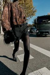 Falda pantalón negra de tiro medio con cierre frontal y hebilla metálica. Presenta bolsillos delanteros y falsos bolsillos de vivo en la espalda.