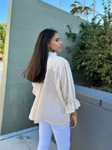 Camisa color crema de broderie con cuello mao con puntilla, mangas tres cuartos con volados y cierre frontal con botones.