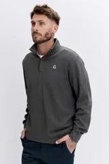 Sudadera de cuello alto con cierre frontal parcial, de manga larga y diseño liso en color gris oscuro. Presenta un pequeño logo bordado en el pecho.