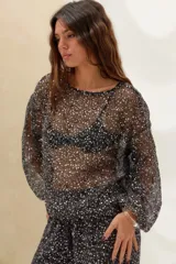 Sweater negro semitransparente de punto con aplicación de lentejuelas plateadas brillantes, cuello redondo y mangas largas holgadas.